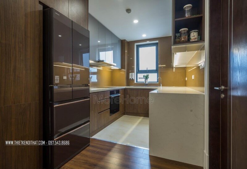 Phòng bếp thu hút ánh nhìn bởi mẫu tủ bếp gỗ công nghiệp và sự kết hợp giữa màu sắc của tủ cùng với kính màu ốp bếp màu vàng. Thiết kế phòng bếp